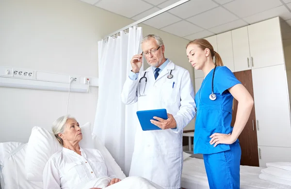 Médico y enfermera visitando a una mujer mayor en el hospital — Foto de Stock