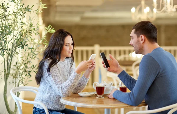 Szczęśliwa para ze smartfonami picie herbaty w kawiarni — Zdjęcie stockowe