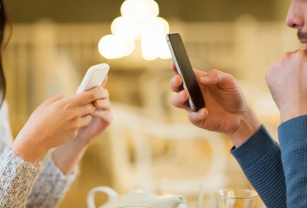 Zbliżenie się pary ze smartfonami w kawiarni — Zdjęcie stockowe