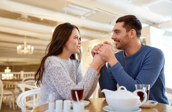 Šťastný pár s čajem drží ruce v restauraci — Stock fotografie