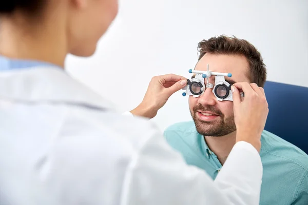 Оптика з пробною рамкою і пацієнткою в клініці — стокове фото