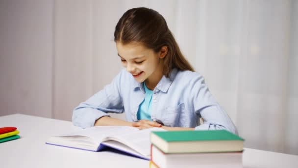 Happy school girl reading book or textbook at home — Stock Video