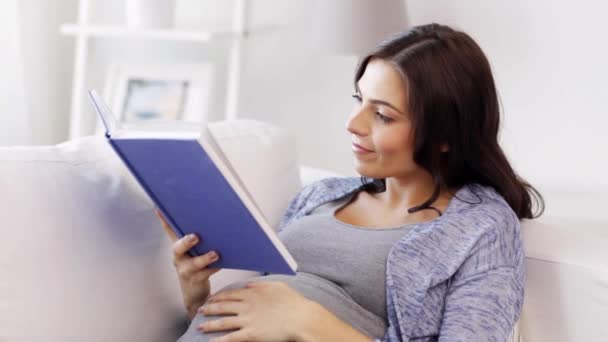 Gelukkig zwanger vrouw lezen boek thuis — Stockvideo