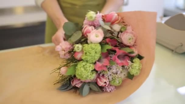 Florista embrulhando flores em papel na loja de flores — Vídeo de Stock