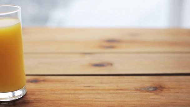 Vaso lleno de jugo de naranja sobre mesa de madera — Vídeos de Stock