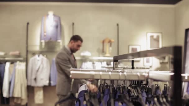 Young man choosing clothes in clothing store — Stock Video