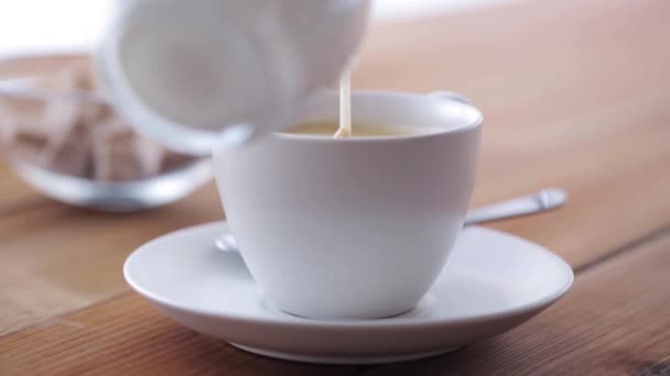 Crema que vierte a la taza de café en la mesa de madera — Vídeos de Stock