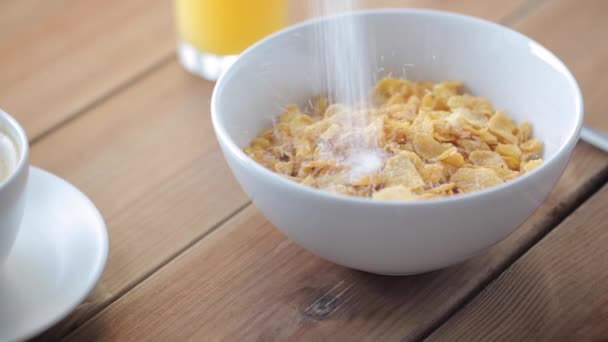 Sugar pouring to corn flakes on wooden table — Stock Video