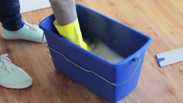 Woman washing and squeezing rag in bucket at home — Stock Video