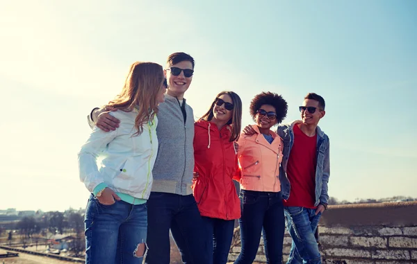 Happy teenage friends walking along city street — Stock Photo, Image