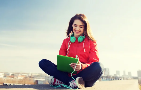 Heureuse jeune femme avec tablette PC et écouteurs — Photo