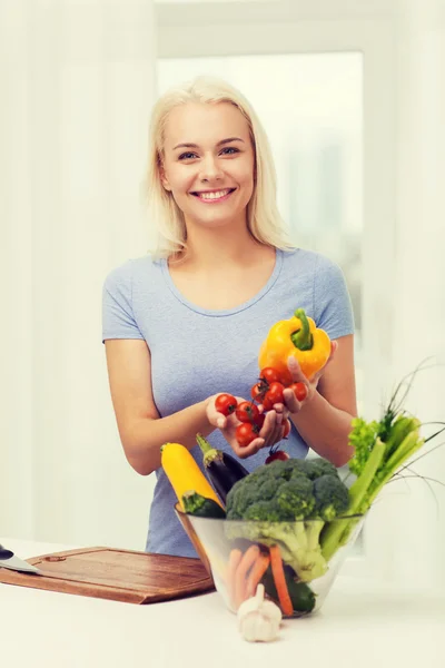 Sorridente giovane donna che cucina verdure a casa — Foto Stock