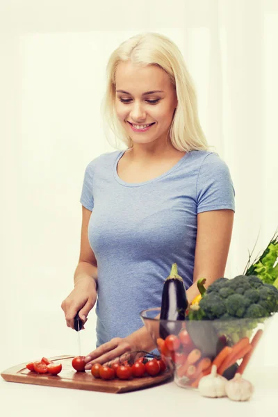 Улыбающаяся молодая женщина, рубящая овощи дома — стоковое фото