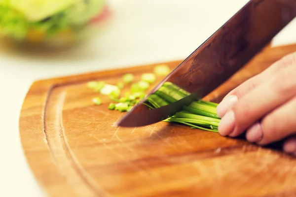 Nahaufnahme einer Frau, die grüne Zwiebeln mit einem Messer hackt — Stockfoto