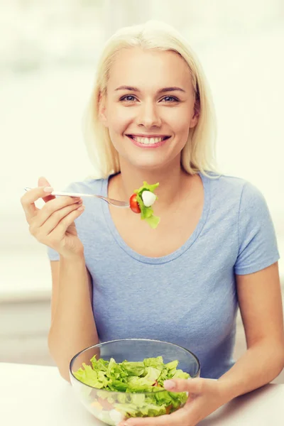 Lachende jonge vrouw salade eten thuis — Stockfoto