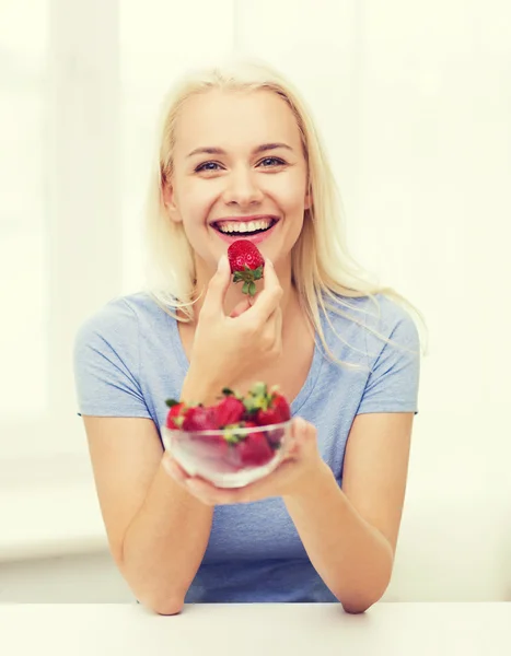 Lycklig kvinna äta jordgubbar hemma — Stockfoto