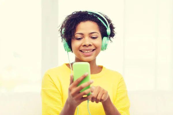 Mujer africana feliz con teléfono inteligente y auriculares — Foto de Stock