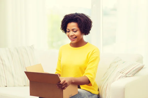 Gelukkig Afrikaanse jonge vrouw met perceel vak thuis — Stockfoto