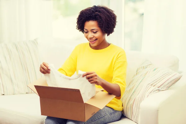 Mujer joven africana feliz con la caja del paquete en casa —  Fotos de Stock