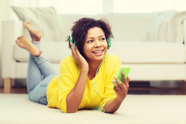 Mujer africana feliz con teléfono inteligente y auriculares —  Fotos de Stock