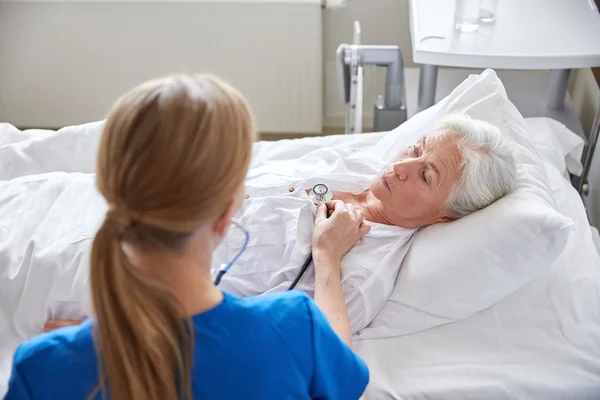 Nurse with stethoscope and senior woman at clinic — Stock Photo, Image