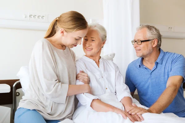 Familia feliz visitando a la mujer mayor en el hospital — Foto de Stock