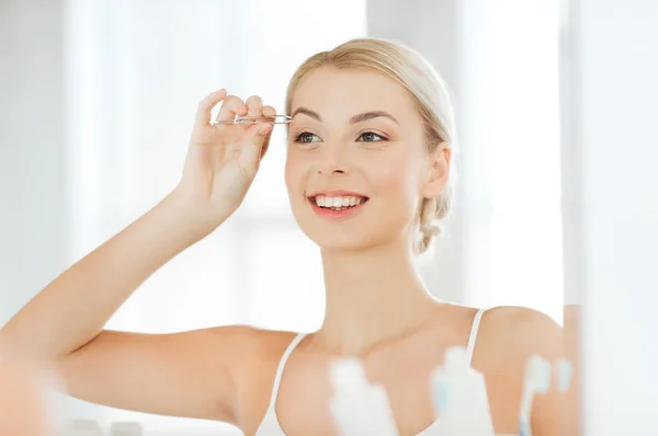 Mujer con pinzas de depilación ceja en el baño —  Fotos de Stock