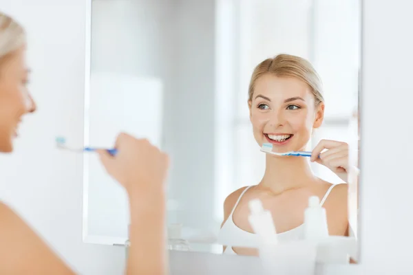 Mulher com escova de dentes limpeza dentes no banheiro — Fotografia de Stock