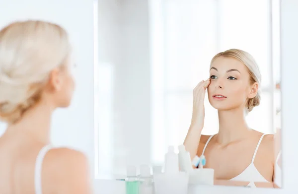 Donna felice che applica la crema per il viso in bagno — Foto Stock