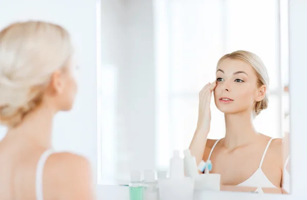 Femme heureuse appliquant crème pour le visage à la salle de bain — Photo