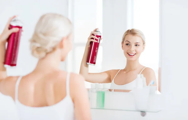 Frau mit Haarspray frisiert ihr Haar im Badezimmer — Stockfoto