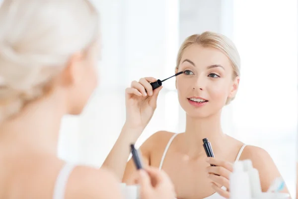 Mulher com rímel aplicando maquiagem no banheiro — Fotografia de Stock