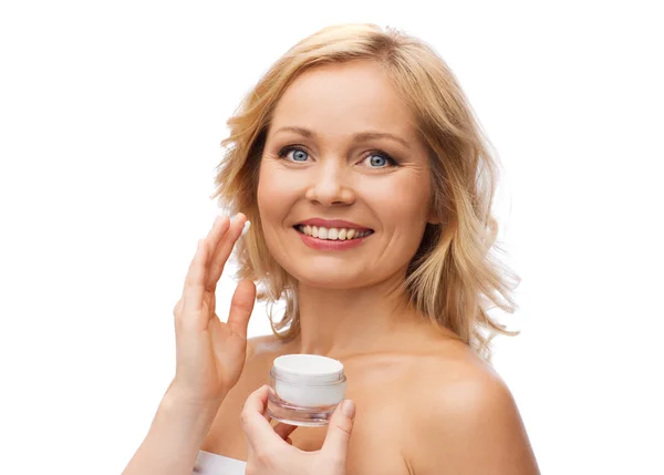 Mujer feliz aplicando crema en su cara — Foto de Stock