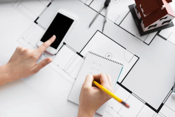 Närbild på händerna med blueprint och smarphone — Stockfoto