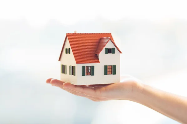 Close up de mãos segurando casa ou modelo de casa — Fotografia de Stock