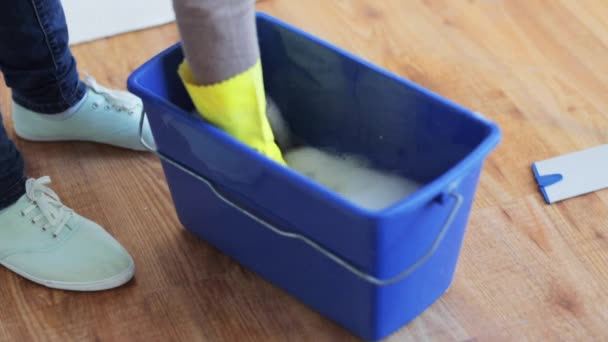 Woman washing and squeezing rag in bucket at home — Stock Video
