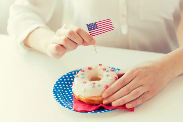Weibliche Hände dekorieren Donut mit amerikanischer Flagge — Stockfoto