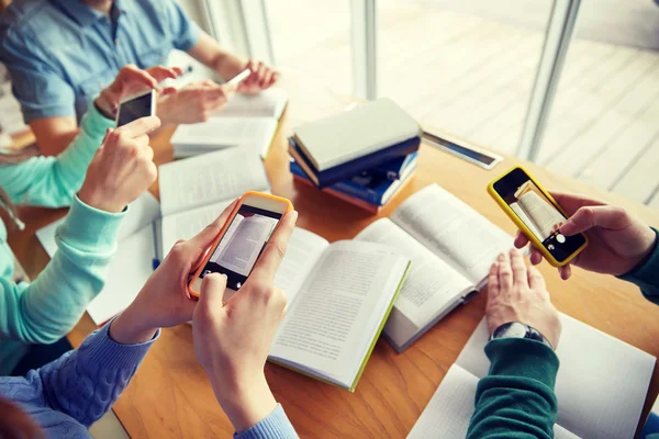 Students with smartphones making cheat sheets — Stock Photo, Image