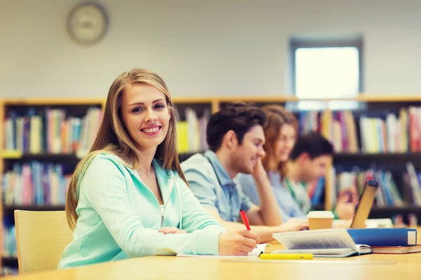 Menina estudante feliz escrevendo para notebook na biblioteca — Fotografia de Stock