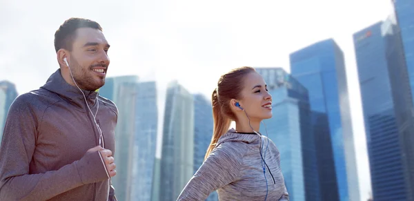 Ευτυχισμένο ζευγάρι με ακουστικά που τρέχουν στην πόλη — Φωτογραφία Αρχείου