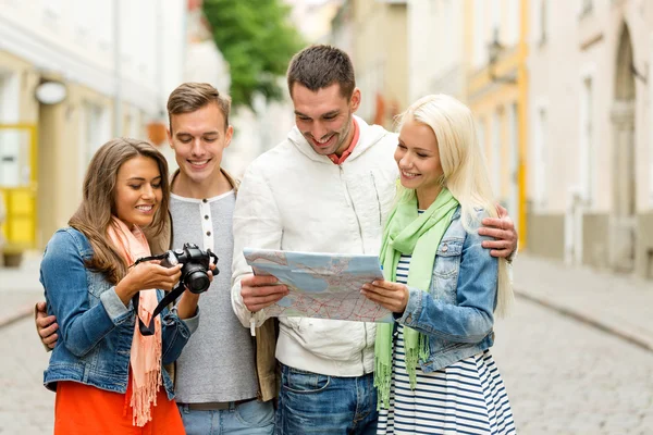 Groep lachende vrienden met kaart en fotocamera — Stockfoto