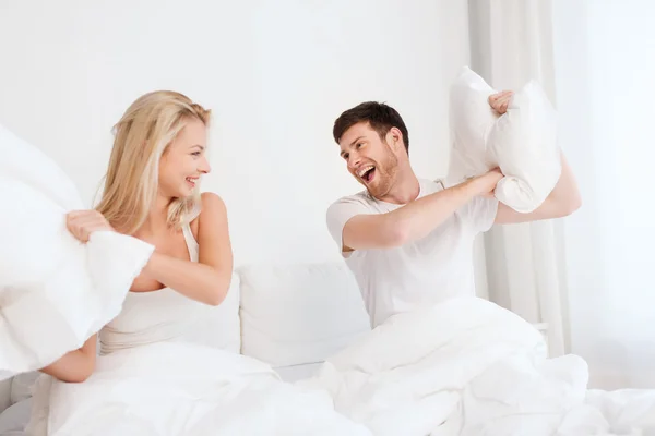 Happy couple having pillow fight in bed at home Stock Picture