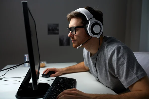 man in headset playing computer video game at home