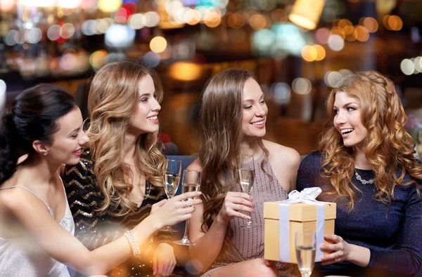 Щасливі жінки з шампанським і подарунком в нічному клубі — стокове фото
