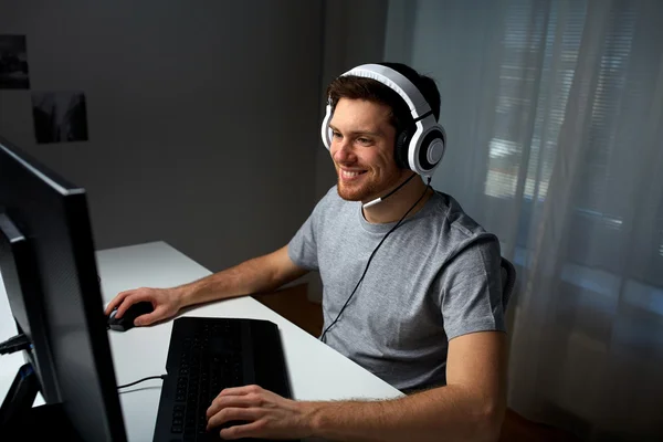 耳机玩电脑视频游戏在家里的人 — 图库照片