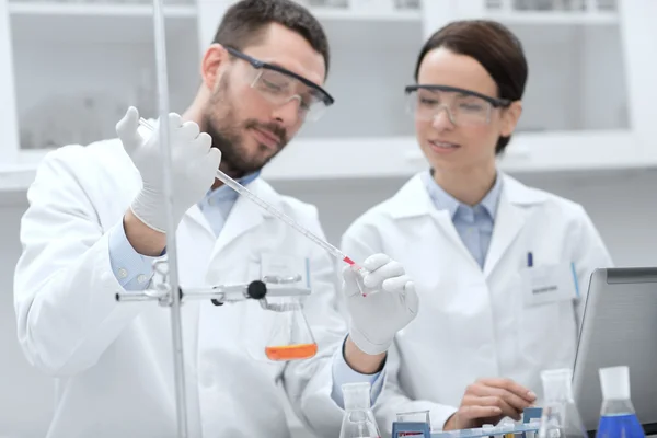 Jóvenes científicos haciendo pruebas o investigaciones en laboratorio — Foto de Stock