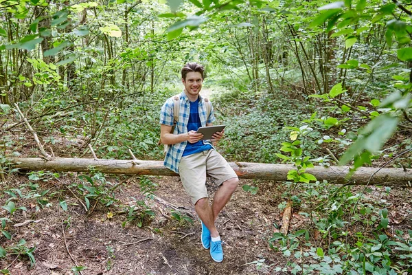 Glücklicher Mann mit Rucksack und Tablet-PC im Wald — Stockfoto