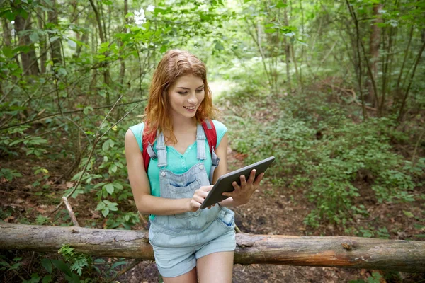 Gelukkige vrouw met rugzak en tablet pc in bos — Stockfoto
