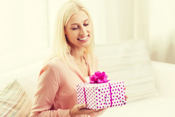 Smilende kvinne med gaveeske hjemme – stockfoto