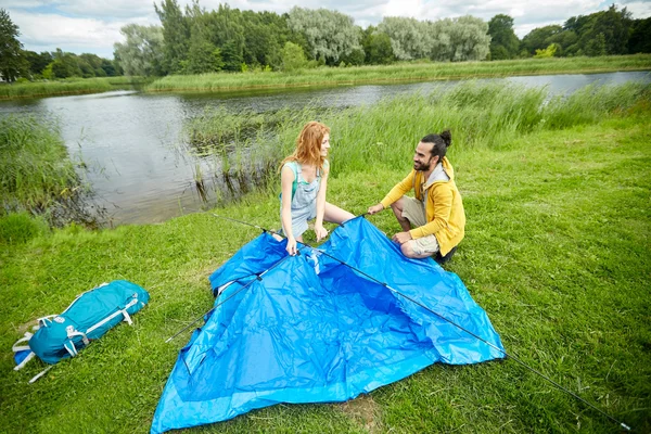 Happy couple setting up tent outdoors — Stock Photo, Image